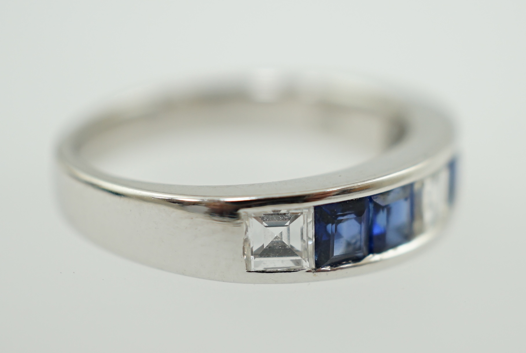 A modern 14k white gold, three stone diamond and four stone sapphire half hoop ring